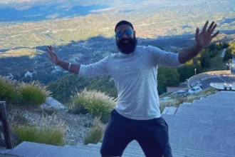 Chapati Hindustani Gamer posing on a mountain staircase with a scenic valley view