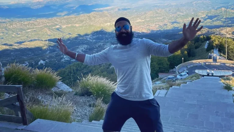 Chapati Hindustani Gamer posing on a mountain staircase with a scenic valley view