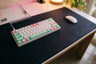 Compact 60 percent white keyboard with pastel keycaps and a mouse on a white desk seen from above