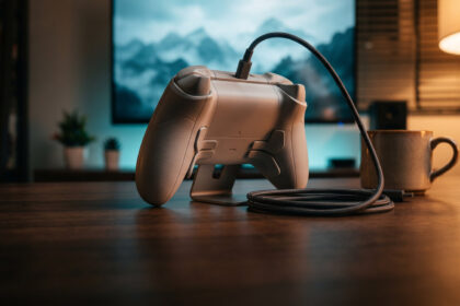 Premium grey gamepad on a stand showing its rear back buttons on a walnut desk at night