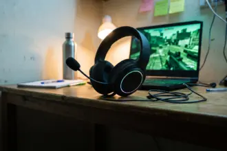Budget wired plastic gaming headset with boom mic on a hostel study table beside a laptop at night