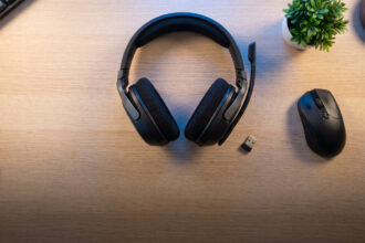 Flagship wireless gaming headset with a small USB dongle on a pale desk seen from above