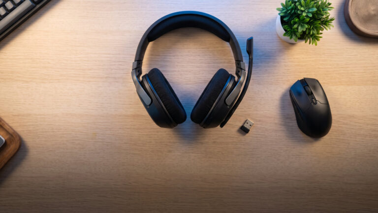Flagship wireless gaming headset with a small USB dongle on a pale desk seen from above
