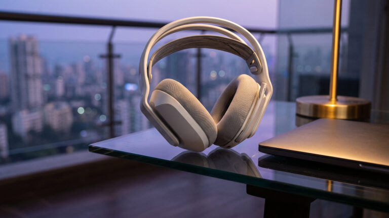 Lightweight white wireless gaming headset on a glass desk in a balcony nook with city lights at dusk