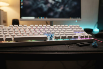 White mechanical keyboard with one keycap removed to show a blue switch, a keycap puller beside it