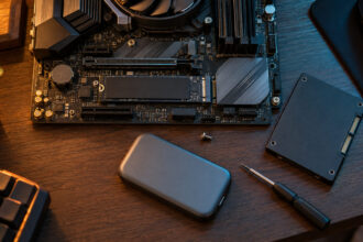 M.2 SSD fitted into a motherboard beside a SATA drive and a portable SSD on a desk seen from above