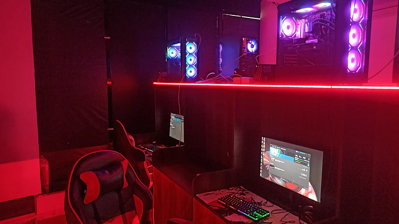 A PC gaming station with a gaming chair under red lighting at Synapse Gaming Cafe