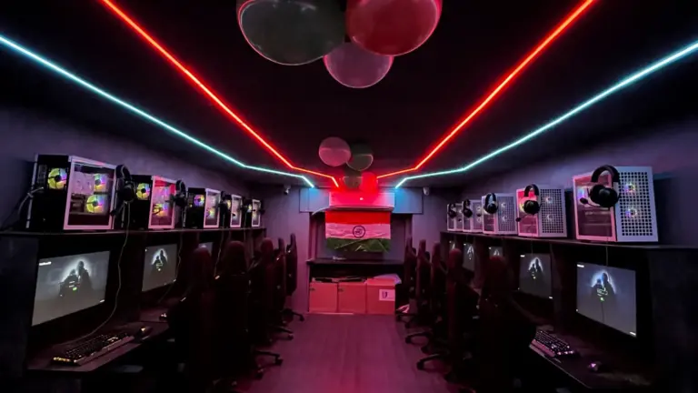 An aisle of gaming PCs under red and teal neon at VoidZone Gaming Cafe, Mumbai